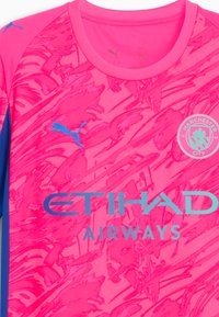 Manchester City-tröja i vibrerande rosa med ett grafiskt mönster, som har blå accenter och logotyperna för Puma och Etihad Airways.