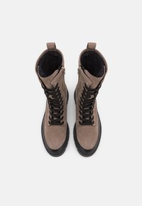 Bruine suède enkellaarsjes met zwarte veters, een gladde textuur, ronde neus en een zijrits. Dikke zwarte rubberen zool met een patroon.