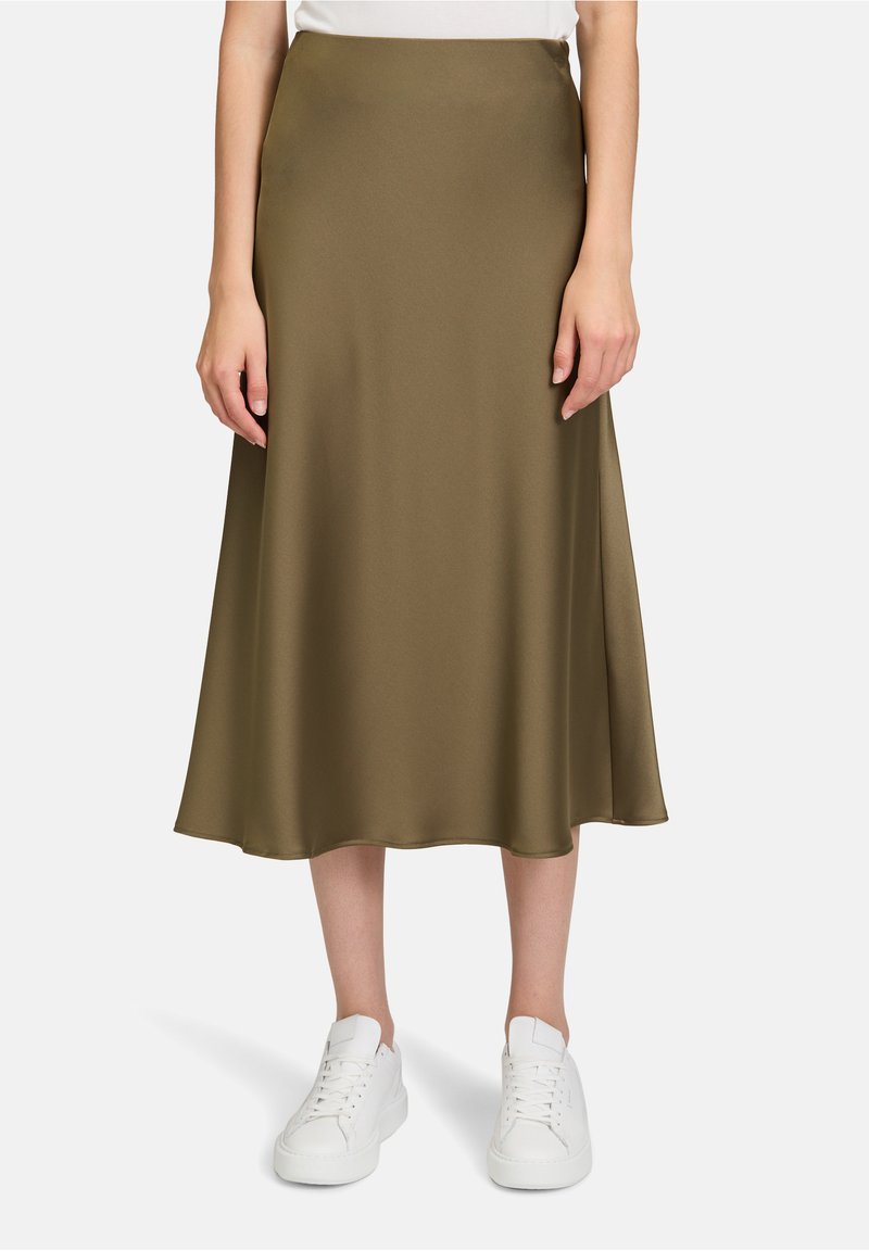 Olivgrüner, satinierter A-Linien-Midirock mit glatter Textur, kombiniert mit weißen Sneakers. Einfaches Design mit einer fließenden Silhouette.