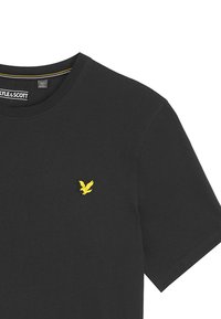 Svart bomull t-shirt med rund halsringning, kort ärm och en liten gul örnlogotyp på vänster bröst.