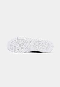 Semelle de chaussure blanche avec des motifs de relief, un design circulaire près du talon et le nom de la marque "HILFIGER" embossé au centre.