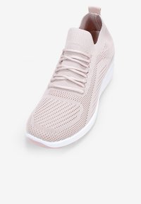 Sneaker a maglia rosa chiaro con tomaia senza cuciture, lacci sottili e suola bianca. Presenta una texture in mesh traspirante e una linguetta sul tallone.