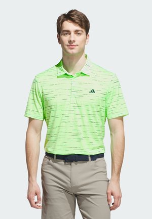 Bright green polo shirt with a textured pattern, featuring a collar and three buttons, paired with light beige pants and a dark waistband.
