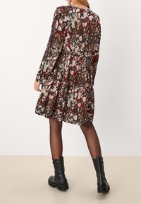 Brun blommig klänning med långa ärmar, volang nederkant och en texturerad tyg. Matchad med svarta ankelboots för kontrast.