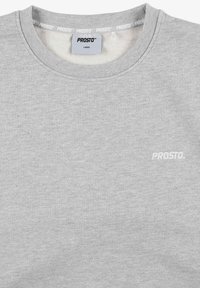 Szara bluza z okrągłym dekoltem, wykonana z miękkiego materiału. Posiada małe białe logo "PROSTO." z przodu oraz prążkowany dekolt.