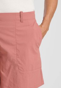 Pantaloni corti rosa realizzati in tessuto leggero con una texture liscia, caratterizzati da una tasca laterale e una vita sagomata.