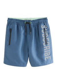 Pantaloncini da bagno blu con vita elastica, coulisse regolabile e due tasche laterali con cerniera. Caratterizzati da un testo verticale "SUBSCRIBE" in grigio chiaro.