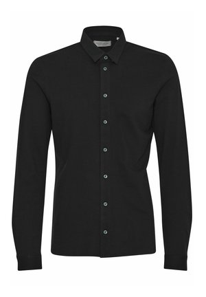 Chemise noire à manches longues en coton avec un col boutonné, dotée de boutons à l'avant dans une couleur sombre et de manches retroussées.