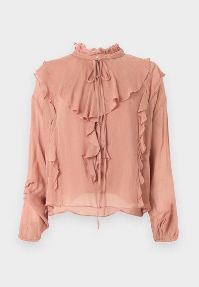 Blouse rose à manches longues avec col montant à volants, détails à volants superposés à l'avant et sur les manches, et fermeture à nouer au niveau du cou.