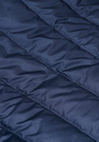 Tela de chaqueta acolchada azul marino con un diseño de acolchado. La textura es suave, con costuras visibles que crean líneas diagonales.
