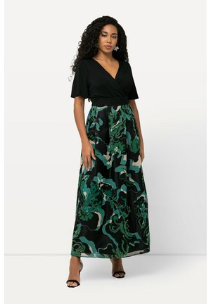 Top nero a maniche corte con scollo a V; gonna lunga con un motivo floreale verde e beige su sfondo nero. Sandali semplici.