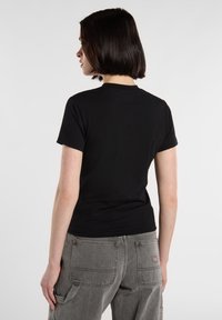 Sort kortærmet t-shirt med en tætsiddende design, glat tekstur og rund hals, parret med lys grå cargo-bukser med store lommer.