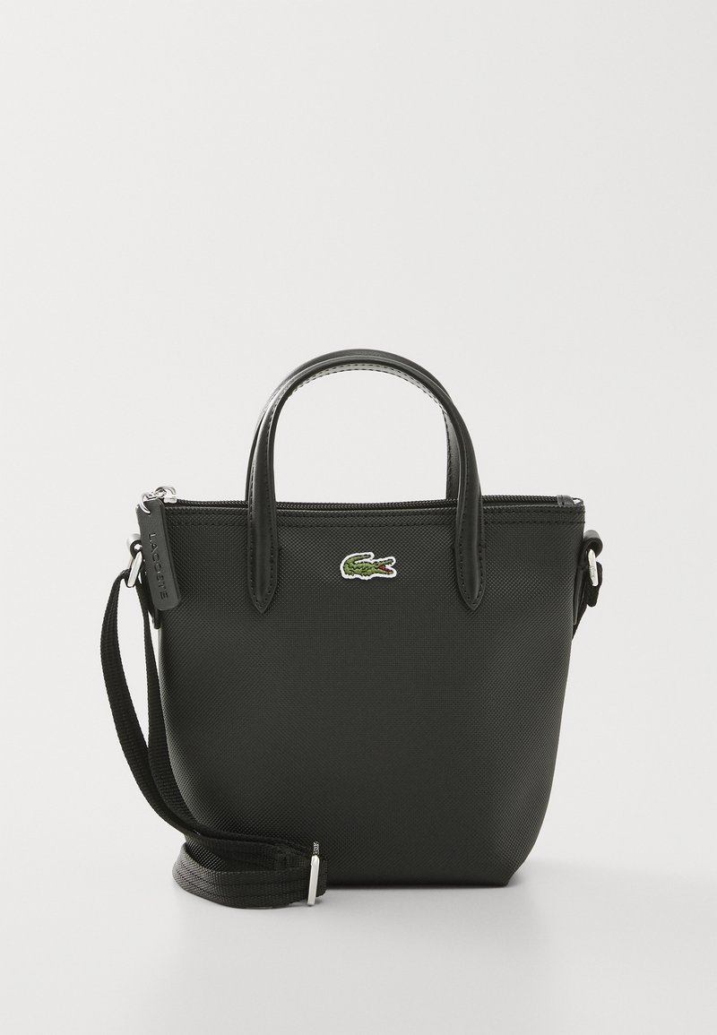 Sac fourre-tout synthétique noir avec doubles poignées, bandoulière amovible, fermeture éclair et accent du logo crocodile vert de Lacoste.