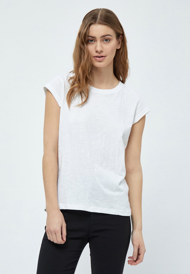 Camiseta blanca de manga corta hecha de un tejido ligero con cuello redondo y puños enrollados. Presenta un ajuste relajado y una textura suave.