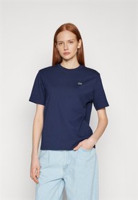 Navy blue cotton t-shirt with a round neckline and short sleeves. Features a small green logo on the chest and a relaxed fit.