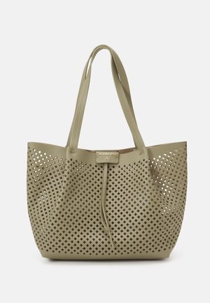 Sac cabas beige avec motif de découpes en forme de losange et doubles bretelles, avec une petite étiquette rectangulaire près du centre supérieur.