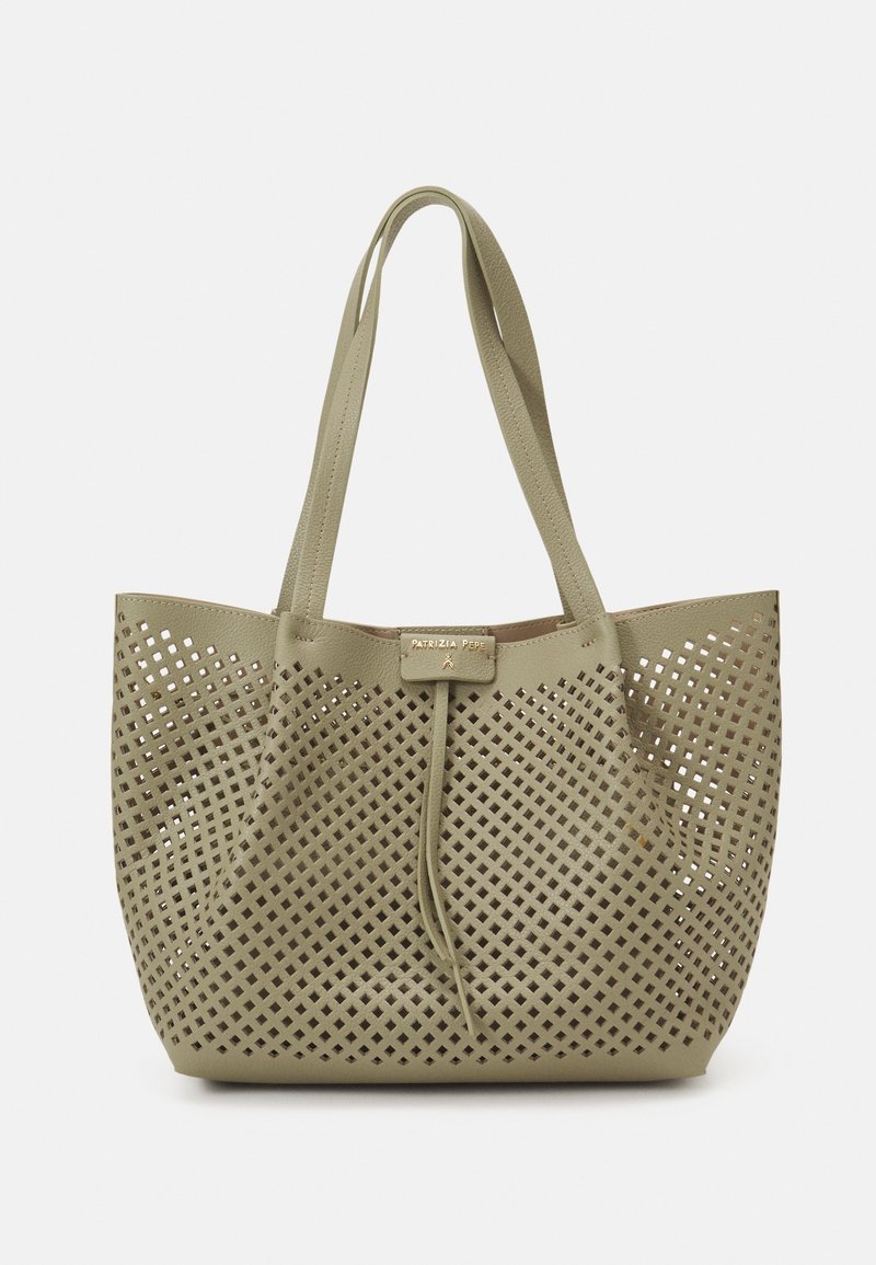Sac cabas beige avec motif de découpes en forme de losange et doubles bretelles, avec une petite étiquette rectangulaire près du centre supérieur.