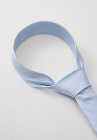 Ljusblå slips med diagonala vita ränder, tillverkad av ett mjukt tyg, med en elegant knut och en spetsig ände för en klassisk look.
