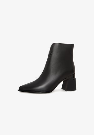 Black ankle boot with a pointed toe and block heel, featuring a smooth leather finish and a sleek zipper on the side.
