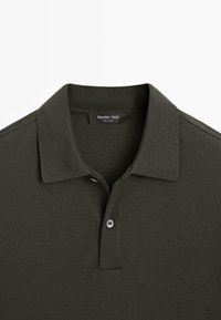 Ciemnozielona koszulka polo z klasycznym kołnierzykiem, plisą zapinaną na dwa guziki oraz miękką, teksturowaną tkaniną. Metka z napisem "Massimo Dutti".