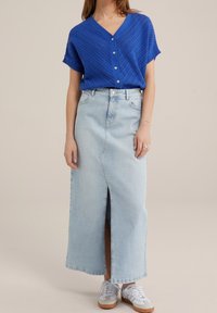 Blå kortärmad, V-ringad stickad topp med ett strukturerat mönster, kombinerad med en ljus denim maxikjol med en framreva och avslappnade sneakers.