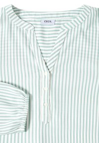 Camisa de rayas verticales verde claro y blanca con tres botones blancos y puño fruncido, etiquetada "CECIL" en el cuello.
