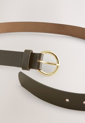 Olivgrönt läderbälte med ett runt spänne i guldfärgad metall, med en slät yta och en brun undersida utan synliga hål.