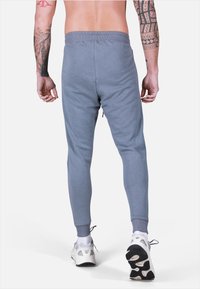 Pantaloni jogger grigio chiaro con una vestibilità affusolata, vita elastica e polsini a coste. Realizzati in un morbido tessuto misto cotone e dal design minimal.