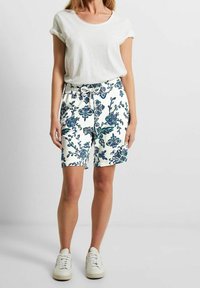 Shorts de estampado floral en blanco con patrones en azul y verde, que cuentan con una cintura elástica con cordón. Combinados con una camiseta blanca sencilla.