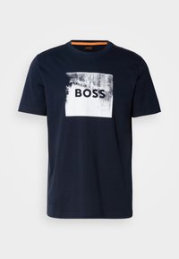 T-shirt in cotone blu navy con una grafica quadrata bianca che presenta la parola "BOSS" in nero. Collo rotondo; maniche corte; texture liscia.
