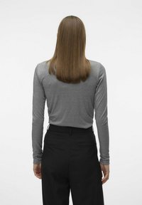 Haut ajusté à manches longues en gris métallique, associé à un pantalon noir taille haute. Texture lisse avec des détails de couture minimalistes, vu de dos.