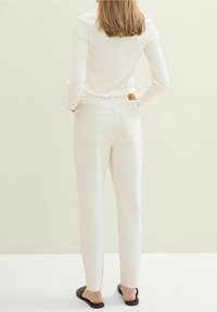 Vita denimbyxor med rak passform och fransade benslut. Toppen har en scalloped kant och etikett på baksidan. Bärs med svarta sandaler.