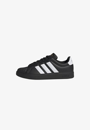 Zapatilla Adidas negra de perfil bajo con tres rayas blancas en los lados, cordones negros y una lengüeta blanca en el talón.