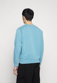 Světlomodrá mikina z bavlny s kulatým výstřihem a žebrovanými manžetami. Design je jednoduchý, s volnějším střihem a bez viditelných vzorů.