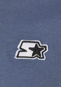 Blue textile background featuring an embroidered logo with a white and black outlined letter "S" and a black star, creating a bold contrast.