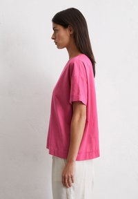 Roze katoenen t-shirt met korte mouwen, ruime pasvorm en een ronde hals. Gladde textuur zonder zichtbare patronen of versieringen.