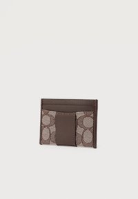 Καφέ δερμάτινη και υφασμάτινη θήκη καρτών με οβάλ σχέδιο και πολλαπλές θήκες για κάρτες σε απλό φωτεινό φόντο.