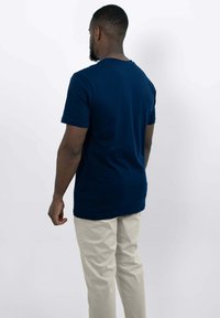 Marineblauwe T-shirt met korte mouwen en een ronde hals, gemaakt van zachte stof. Gecombineerd met lichtbeige broek in een relaxte pasvorm.