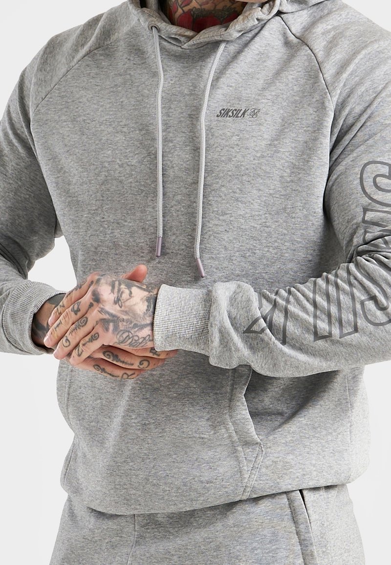 Gray hoodie with a drawstring hood and ribbed cuffs, featuring a logo on the chest and large text design on the sleeve. Soft fabric texture.
