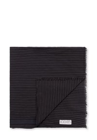 Écharpe noire avec des rayures blanches, en tissu léger, bords effilochés, pliée avec une étiquette de logo dans le coin.