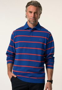 Blå långärmad polo med röda horisontella ränder, som har en krage och logotyp på bröstet. Tillverkad av bomullsliknande material.