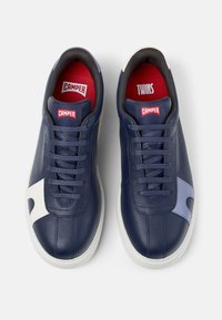 Pair of navy leather Camper sneakers with white and light blue accents, white soles, red insoles, and Camper logos on tongues.