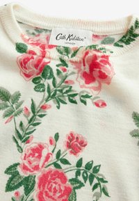 Blumenstrickpullover mit einer cremefarbenen Basis, rosa Rosen und grünen Blättern. Mit einem runden Ausschnitt und einem Etikett mit der Aufschrift "Cath Kidston, London."
