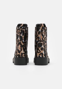 Botas de tobillo con estampado de leopardo en un tejido negro texturizado, con suela gruesa negra y detalles sutiles en marrón y beige claro.