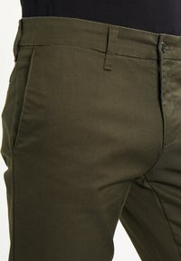 Khaki groene broeken gemaakt van een katoenmix, met een rechte snit, standaard vijfzakkenontwerp en metalen knoopsluiting.