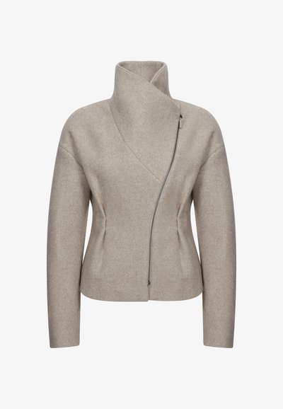 Beżowa kurtka z wełny z wysokim kołnierzem, asymetrycznym frontem i bocznym zamkiem błyskawicznym. Posiada dopasowany krój i ukryte kieszenie.