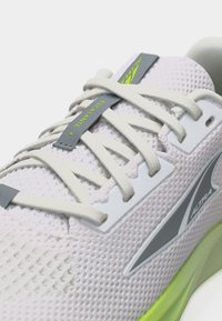 Λευκό αθλητικό παπούτσι τρεξίματος από δίχτυ με ανοιχτογκρίζα κορδόνια, γκρίζες και νέον πράσινες λεπτομέρειες, με τα λογότυπα "Escalante 4" και "Altra".