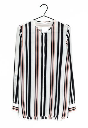 Bluzka na długi rękaw na guziki z pionowymi czarnymi, białymi i czerwonymi paskami, okrągłym dekoltem i mankietami na rękawach zawieszona na czarnym wieszaku.