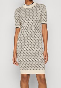 Robe en maille crème avec un motif en losanges, dotée de manches courtes et d'un col et des poignets côtelés en marine. Coupe ajustée et longueur genou.