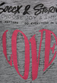 Gray t-shirt featuring large pink "LOVE" text embellished with small rhinestones, with additional text above in black, casual font.